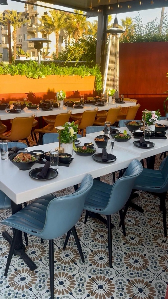 Bei's outdoor patio set for a long dinner, with patterned tile floors and palm trees